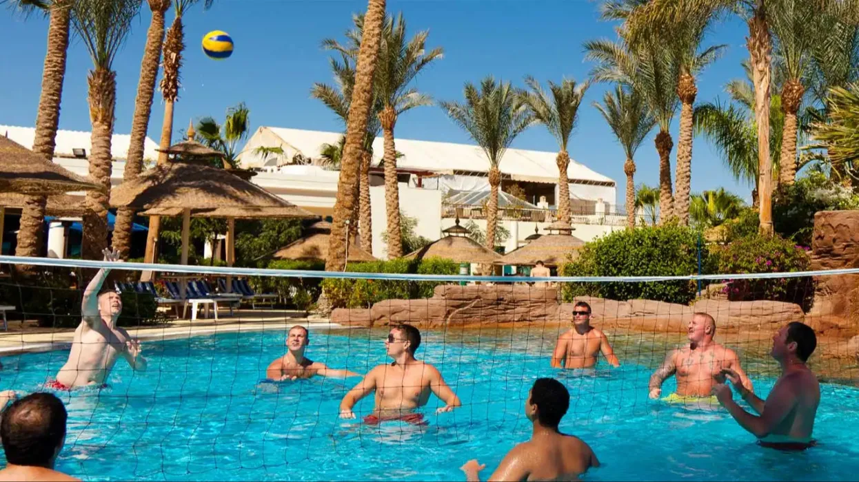 A group of people playing volleyball in the Miramar Al Aqah Resort's outdoor pool