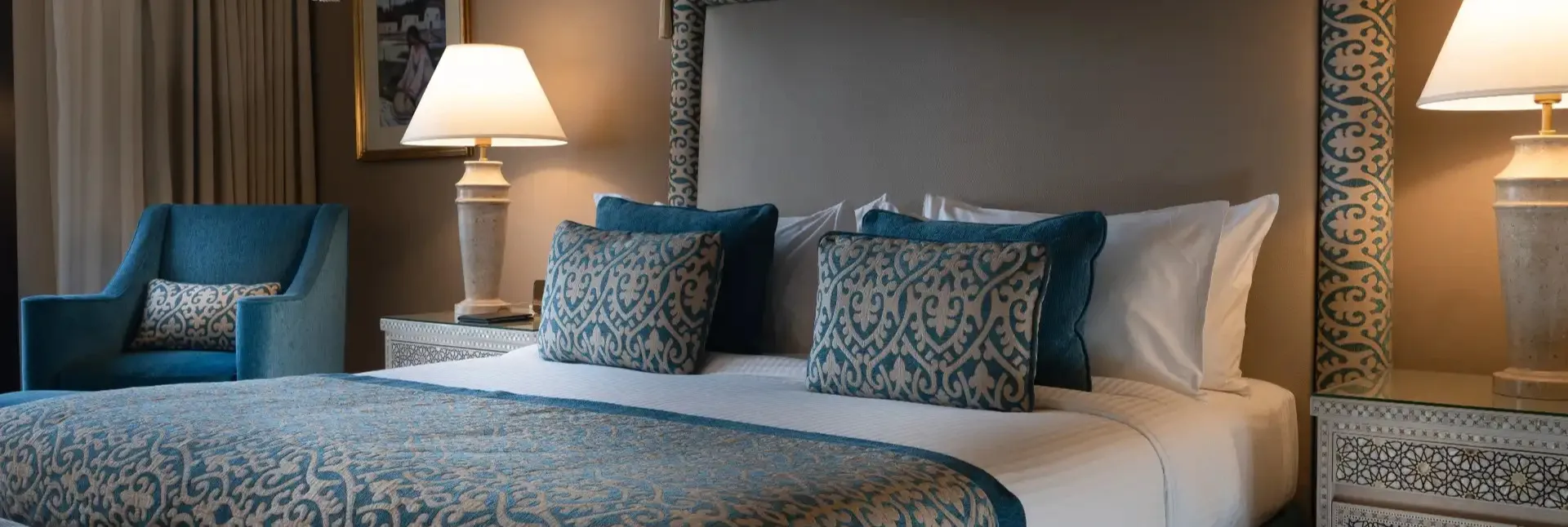 A queen size bed and table lamps at the Villa Ocean View in Miramar Al Aqah Beach Resort